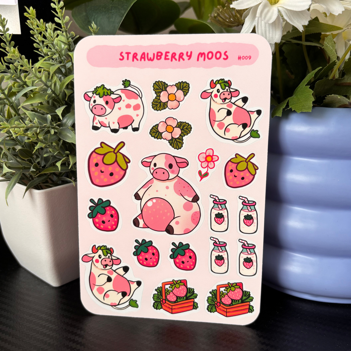 Sticker sheet with cartoon cows and strawberries on a pink background, surrounded by plants and flowers.