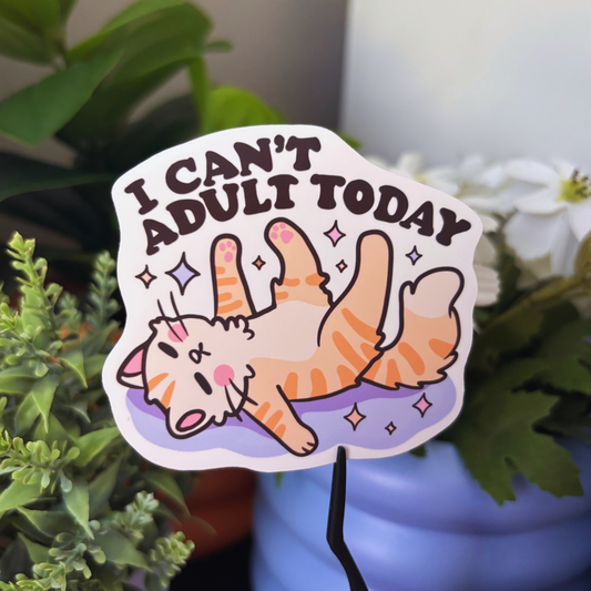 A white sticker features an orange cat lying on its back with the text "I Can't Adult Today".