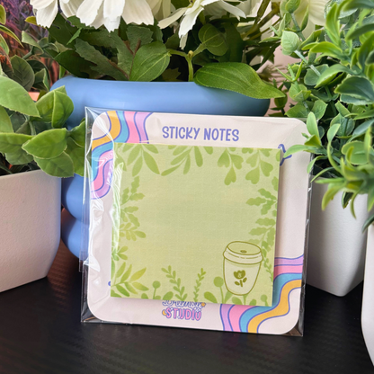 A matcha and leaves sticky notes pad is displayed among green plants.