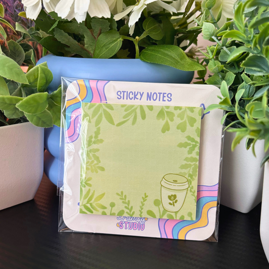A matcha and leaves sticky notes pad is displayed among green plants.