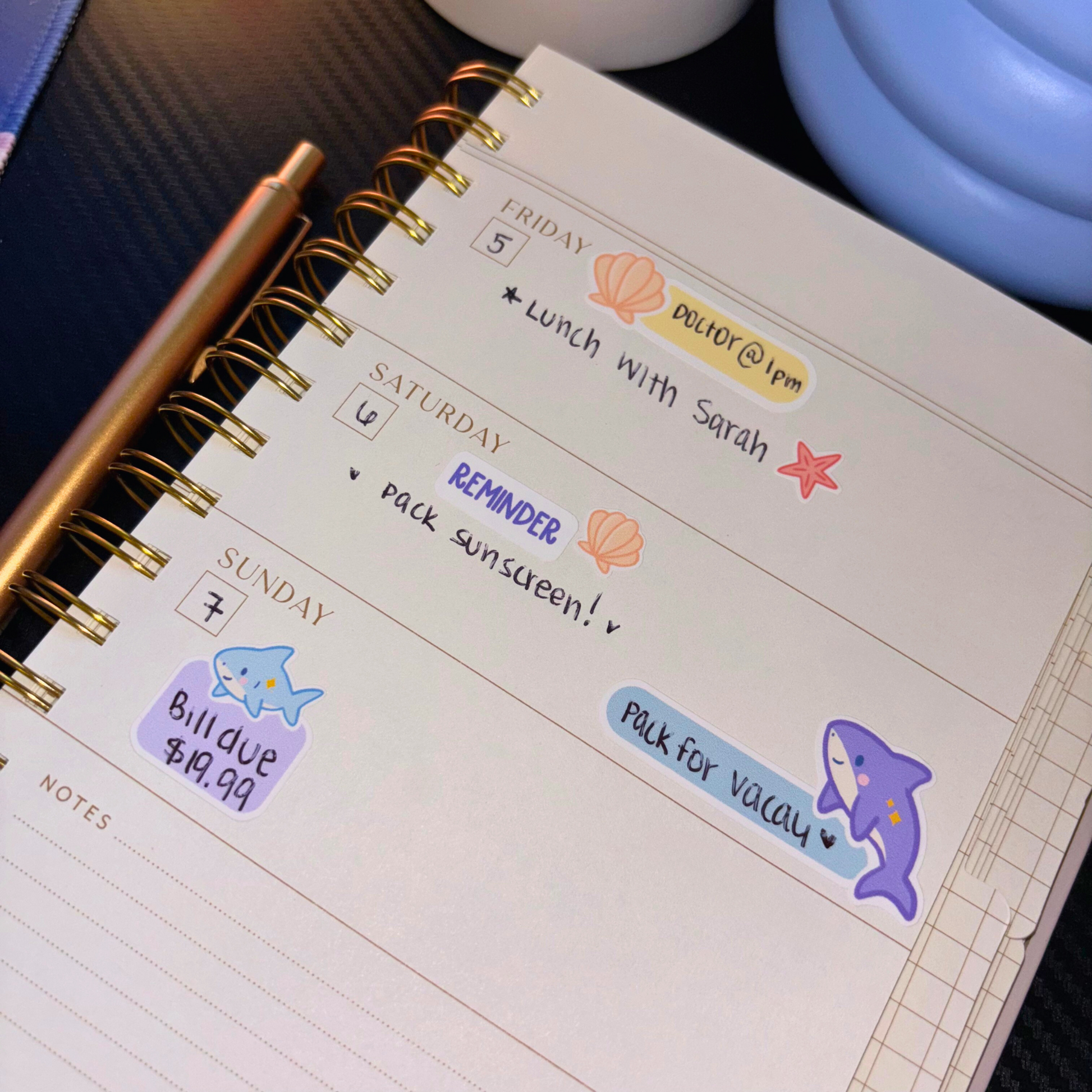 A planner with ocean-themed stickers for Friday, Saturday, and Sunday.
