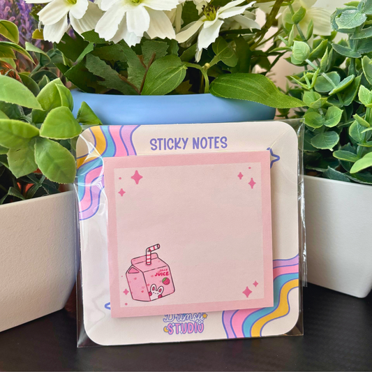 Pink sticky notes with a juice box design are displayed among green plants.